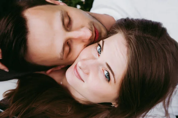 Young loving couple outdoors lying on grass, top down view.