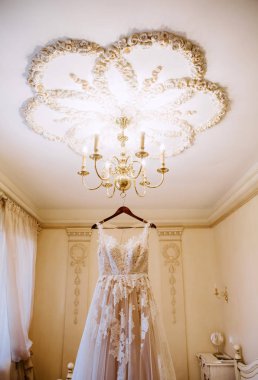 Lüks odada asılı güzel fildişi gelinlik. 