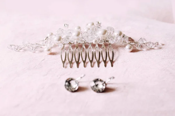 Bridal jewelry arranged on the pink table. Pearl hair accessories and earrings.