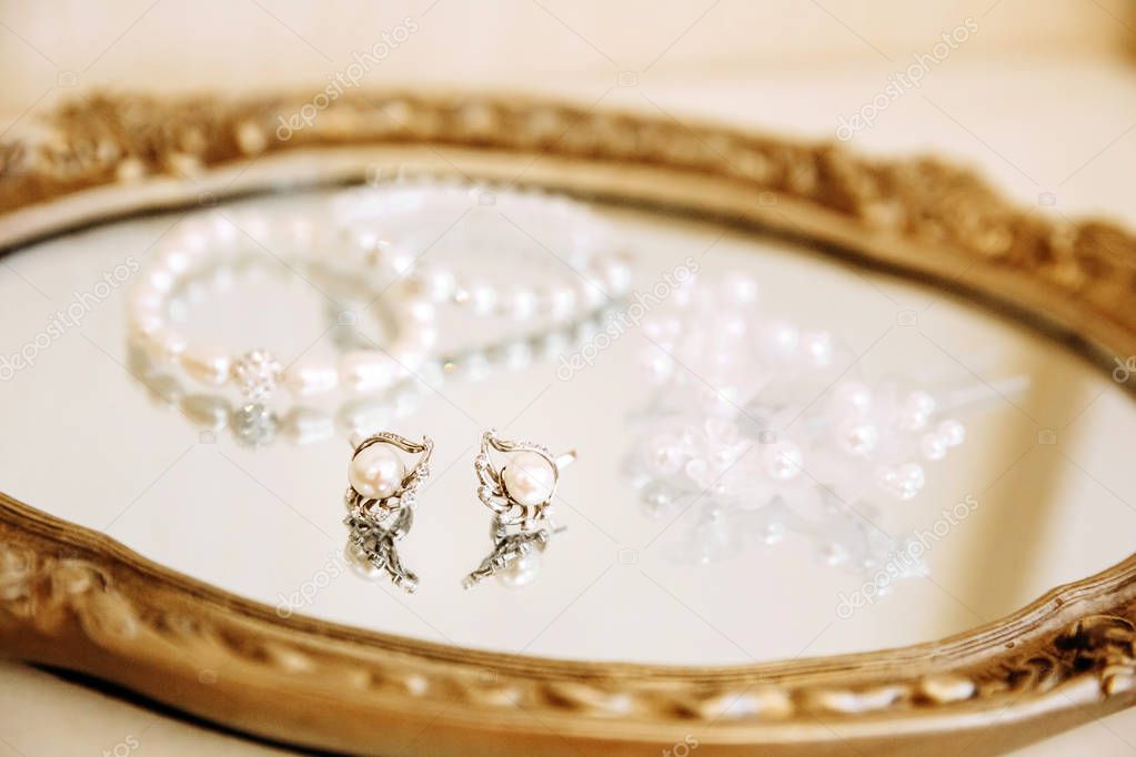 Pearl jewelry placed on a golden mirrored plate.