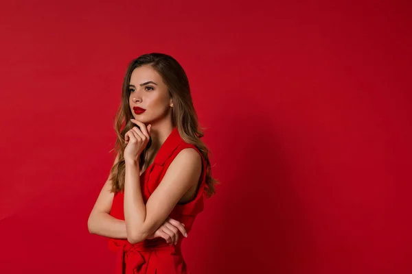 Ritratto di giovane bella donna elegante che sorride distogliendo lo sguardo sullo sfondo rosso . — Foto Stock