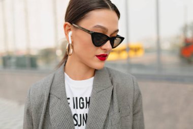 İş merkezinde iş günü yürürken kulaklıkla müzik listeleme çekici mutlu kadın 