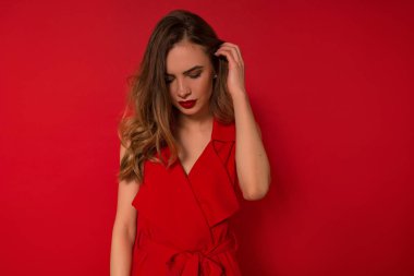 Çarpıcı Avrupalı kadın saçlarına dokunuyor ve aşağı bakıyor. Kırmızı gece elbisesi içinde romantik bayan Kapalı portre