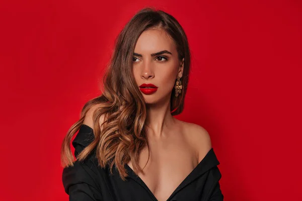 Estudio de imagen de la atractiva elegante mujer joven con el pelo dorado, labios rojos y ganancias sobre fondo rojo —  Fotos de Stock