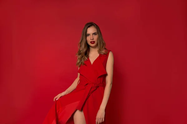 Elégant jeune femme à la mode portant robe rouge fantastique posant sur fond rouge isolé — Photo