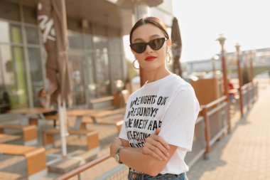 Mutlu büyüleyici genç kadın beyaz t-shirt ve kot müzik ile sokakta ayakta giyen ve güneşli bir gün zevk