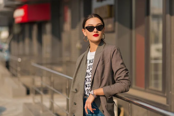 Foto de mujer morena sonriente feliz vistiendo ropa moderna caminando en la ciudad en soleado día de primavera — Foto de Stock