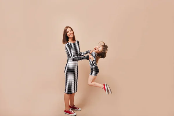 Retrato completo de mujer bonita con hija pequeña usando teléfonos inteligentes sobre fondo beige, concepto familiar — Foto de Stock