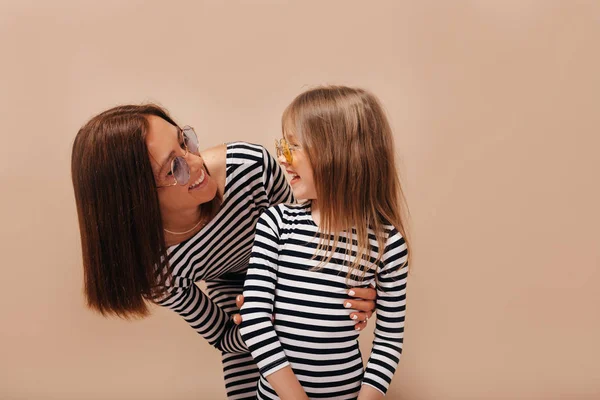 Happy dark-haired woman with short hairstyle looking at her smile charming girl and have fun on isolated background — Stok Foto