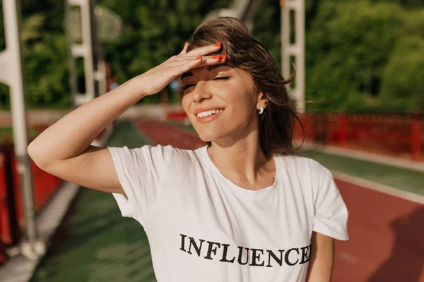 Elle yüz kaplayan açık kahverengi saçları ve gülümseyen sevimli çekici Avrupalı kadın 