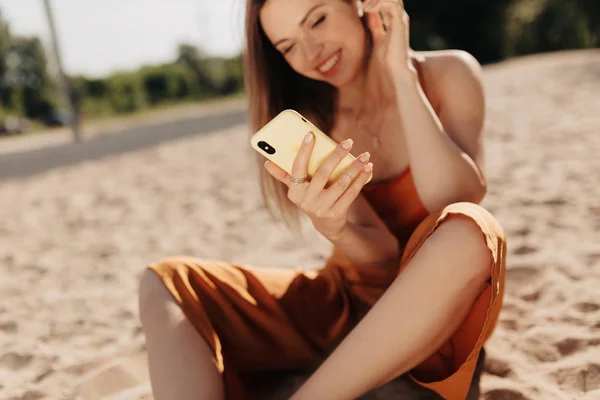Gewas frame van mooie aantrekkelijke meisje dragen zomer kleren luisteren muziek en het gebruik van smartphone op zomer Sunny Beach — Stockfoto