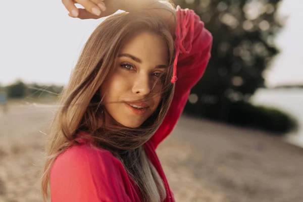 Venku zblízka portrét kouzelné půvabné dámy s růžovou košilí, která se dívá na kameru — Stock fotografie