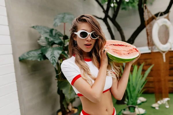 Bingkai horisontal wanita menawan muda dengan semangka mengenakan baju renang dan kacamata hitam fashion — Stok Foto