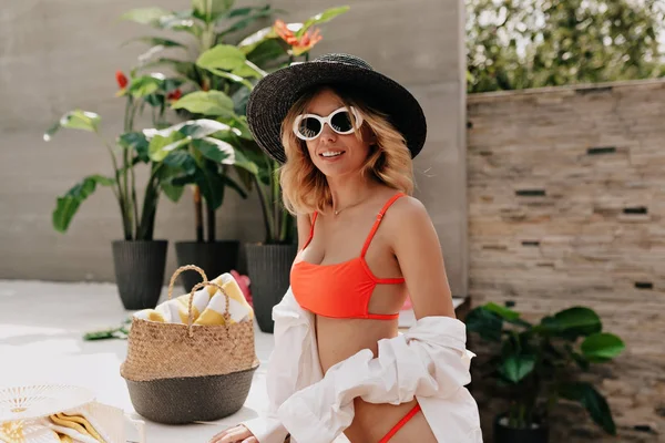 Turuncu bikini ve beyaz gömlek giyen şapka ve moda güneş gözlüğü beyaz sarışın kadın 