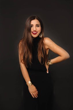 Siyah takım elbiseli, uzun siyah saçlı ve parlak makyajlı şık bir kadın. 