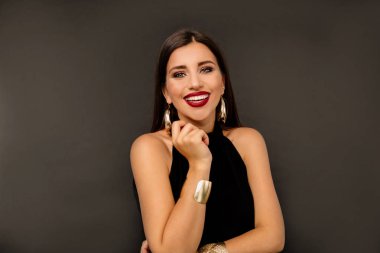 Siyah elbise ve altın giyen neşeli bir güzel kız portresi izole siyah arka plan üzerinde ayakta kazanç