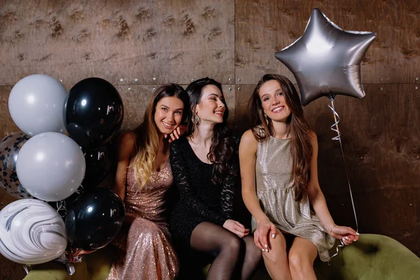 Üç mutlu, mutlu, balonlu, esmer elbiseli kadın.