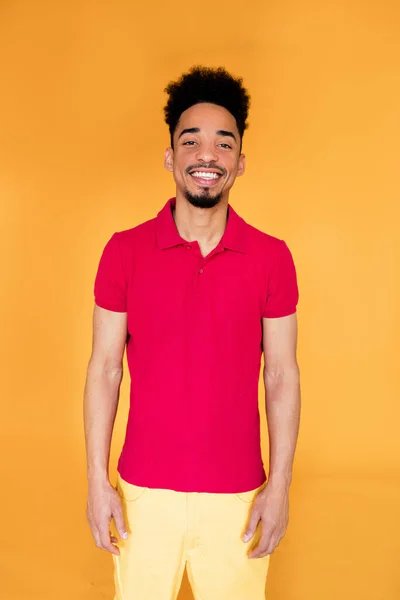 Sonriente joven afroamericano sonriendo confiado en la cámara con ropa de verano brillante. Grabado en estudio. Emoción humana facial positiva . —  Fotos de Stock