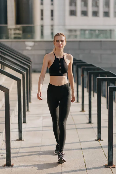 Spor takım elbise giyen ve spor meydanında yürüyen çekici bir kadının tam boy portresi. 