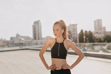 Şehirdeki fitness antrenmanından önce kadın antrenmanı. Sağlıklı genç bir kadın dışarıda ısınıyor ve başka tarafa bakıyor. Yüksek kalite fotoğraf