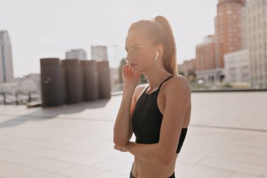 Spor meydanında kulaklıkla müzik dinleyen çekici atletik kızın yan görüntüsü. Yüksek kalite fotoğraf