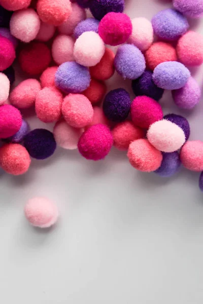 Round pink and purple fluffy balls pompoms on white background