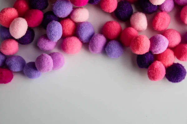 Round pink and purple fluffy balls pompoms on white background