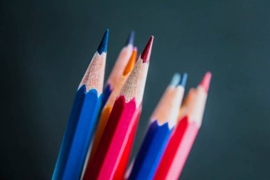 Siyah bulanık arka planda renkli kalemler tutma