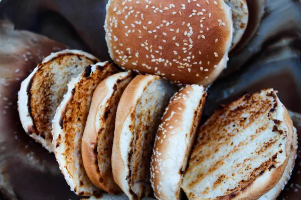 Metal bir kase susam ile ızgara hamburger çörekler.
