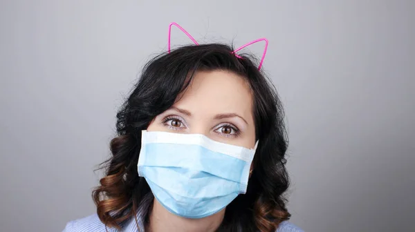 Woman wearing protection face mask against coronavirus. Woman in a mask and cute headband with cat ears. Medical mask, Close up shot, Select focus, Prevention from covid19