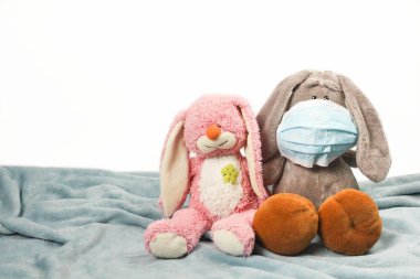 Maskeli hasta, üzgün, peluş bir oyuncak. Grip salgını virüsü bakterisi. Pelüş eşek ve pembe tavşan oyuncağı koruyucu maske takın, Coronavirus konseptine karşı koruyun.