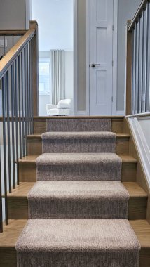 Zarif merdiven yumuşak halı ve ahşap basamaklar içeriyor, doğal ışıkla aydınlık bir odaya açılıyor, sıcak ve davetkar bir ortam yaratıyor.