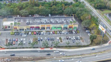 Orlando FL, United States - December 31, 2024: Aerial perspective of shopping center featuring various stores and a bustling parking lot near highway