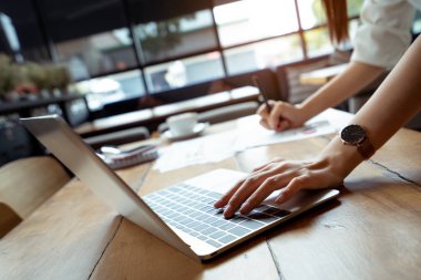 İş işkadını, Çizelgeler ve grafikler dijital dizüstü bilgisayar, gözlük, Not, coworking, kahve ile not yazma onun acele analiz el işaretleme planı gelir dengesi kazanç ve rapor.