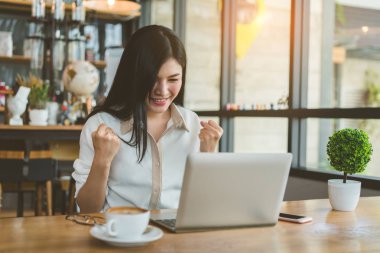Çevirmen güzel Asyalı kadın başarı iş dijital dizüstü bilgisayarınızla mutlu proje ve işyeri kahve dükkanında akşam windows yakınındaki sakin ol.