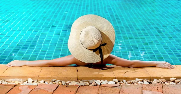 Bikini woman in pool relaxing with cocktail sunglasses, young asian beautiful sexy female resting in vacation on summer season with hat at resort swiming pool