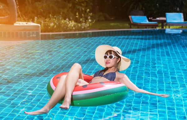 Woman asian bikini swimming pool sitting on watermelon rubber ring with sun hat relaxing vacation enjoying on tropical summer season.