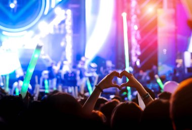 El hareketi seviyor parmak konser sahne ışıkları kalabalık ya da izleyici sanatçı bant Müzik Festivali arka görünümünde, sahne ışıkları parlayan etkisi ve insanlar fan seyirci siluet yükselterek el şeklinde kalp yaptırın