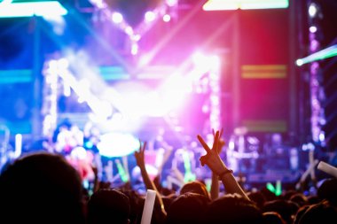 El jest zafer parmak konser aşamada kalabalık ya da izleyici sanatçı grup Müzik Festivali arka görünümünde ile sahne ışıkları etkisi parlak ışıklar ve insanlar kadar eller yükselterek seyirci siluet fan