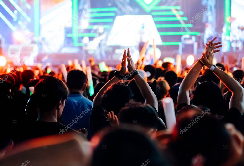Crowd clap or hands up at concert stage lights and people fan audience silhouette raising hands in the music festival rear view with spotlights glowing effect