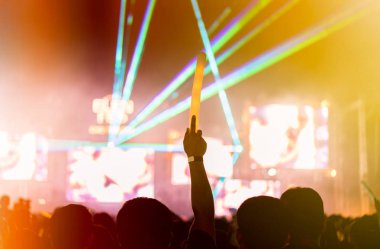 Kalabalık eller ya da Müzik Festivali arka görünümünde holding spot parlak etkisi ve duman ile ışıklı çubuk yetiştirme konser sahne ışıkları ve insanlar fan seyirci silueti