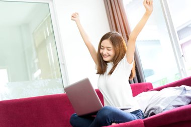 Genç Asyalı kız serbest tembel ve mutlu başarı, bitirmek, dizüstü bilgisayar projesi ile sabah evde kanepe üzerinde office tatil çalıştıktan sonra tamamlamak.