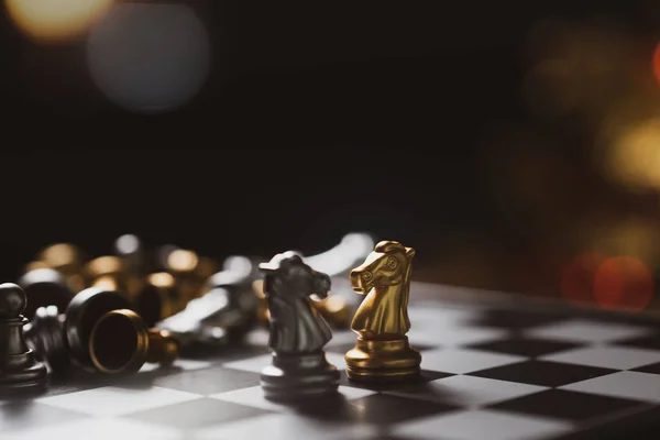 Gold and Silver Chess game knight staying on chessboard,Business planing strong concept with black background