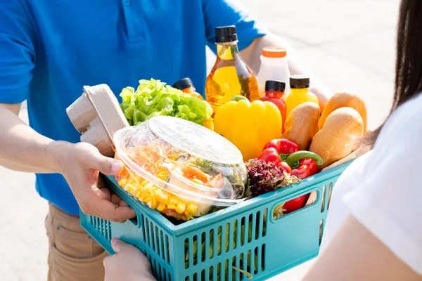 Food Deliver Asian man in blue uniform give fruit and vegetable to receiver customer front house, fast express grocery service when crisis coronavirus, covid19 new normal lifestyle concept.