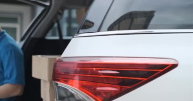 Paketi alan ve ön alıcıyı kontrol eden maskeli bir teslimatçı, bagaj vagonunda virüs yayılırken kargo sosyal mesafesini kontrol ediyor..