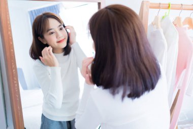 Genç Asyalı kadın makyaj malzemelerini kontrol ediyor, alışveriş ve moda mağazası, evde kıyafet yaşam tarzı var..