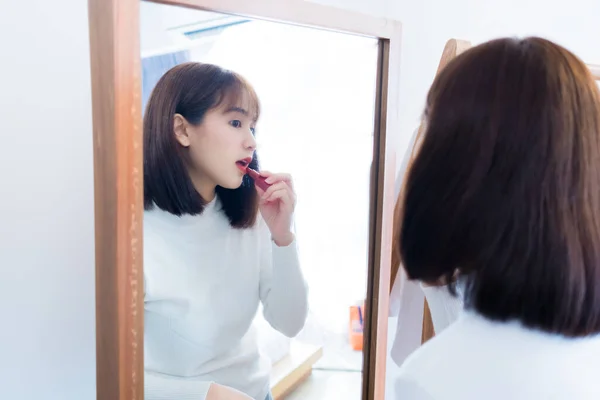 选择化妆的亚洲女人每天都会在家里的镜子前快乐地涂上口红和微笑 看起来像生活方式 — 图库照片
