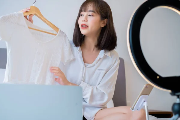 아리따운 아시아 의상의 옷걸이에 옷가지를 녹화하는 행상인 마케팅을 미디어를 이용하는 — 스톡 사진