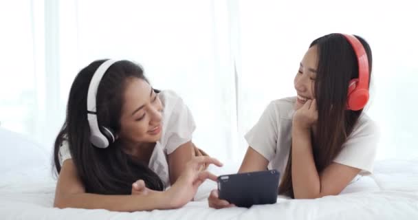 Két Fiatal Ázsiai Fekszik Ágyban Fülhallgatót Visel Videohívások Közben Miközben — Stock videók