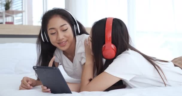 Két Fiatal Ázsiai Fekszik Ágyban Fülhallgatót Visel Videohívások Közben Miközben — Stock videók